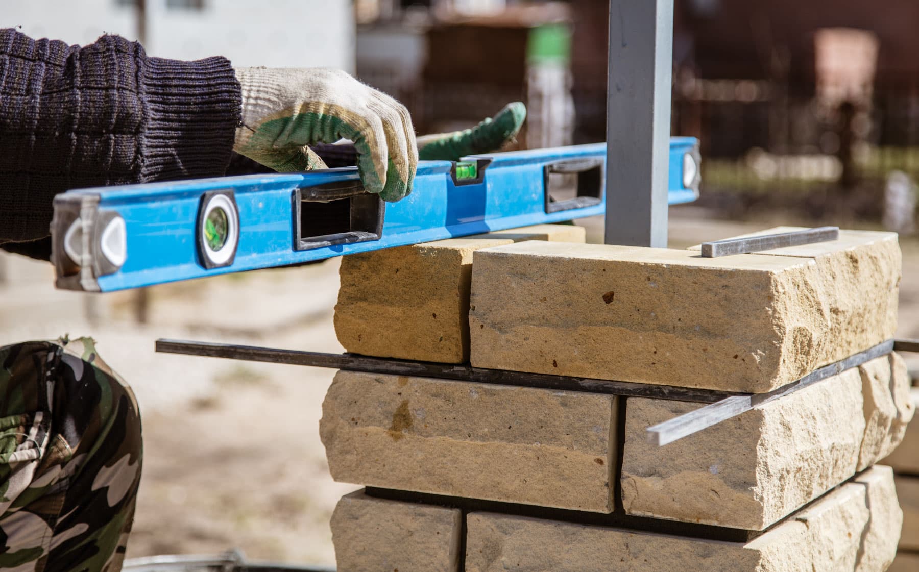 Mason levelling stone block course with a spirit level
