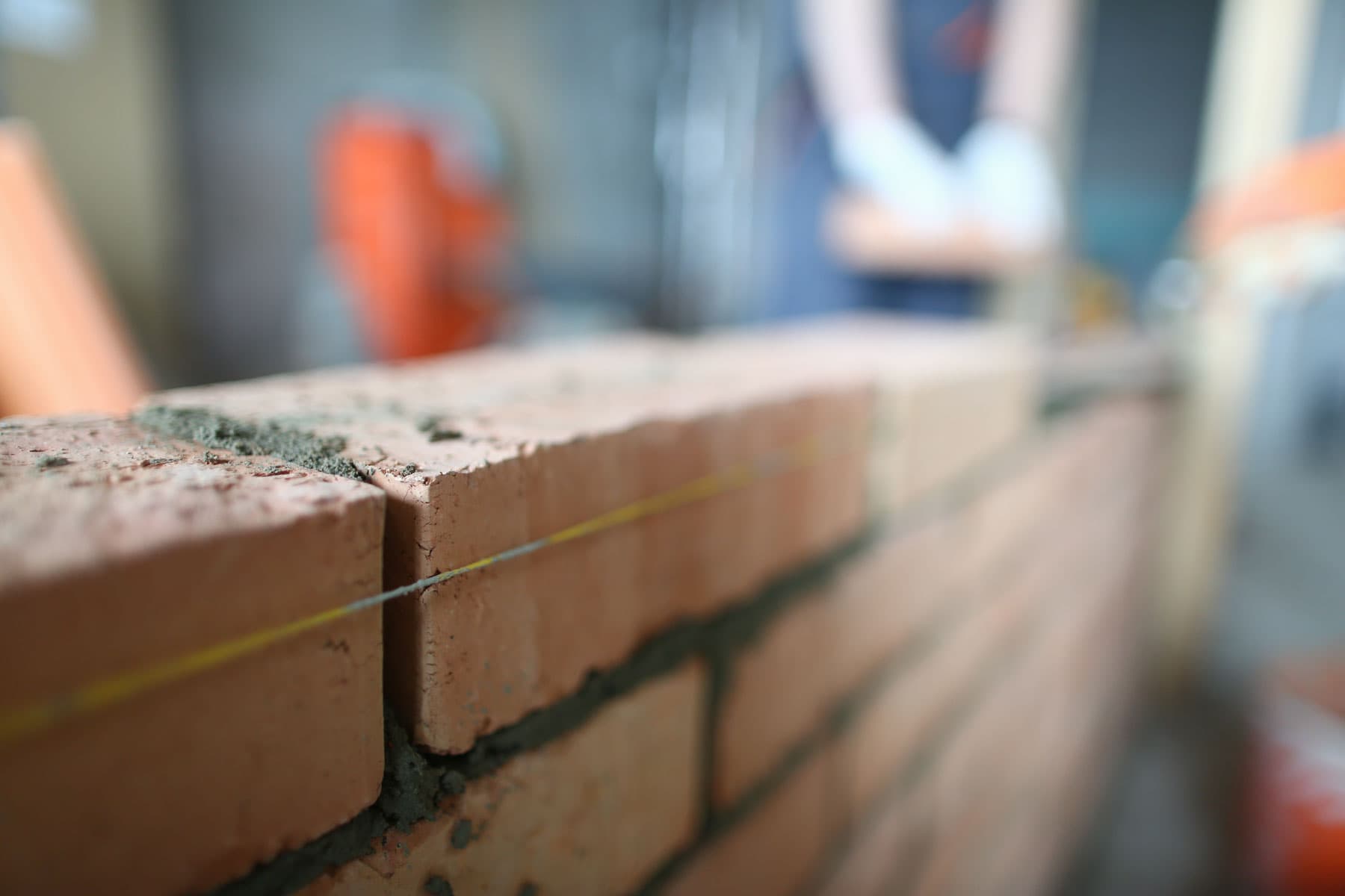 Close-up of a fresh brick course being laid with string line