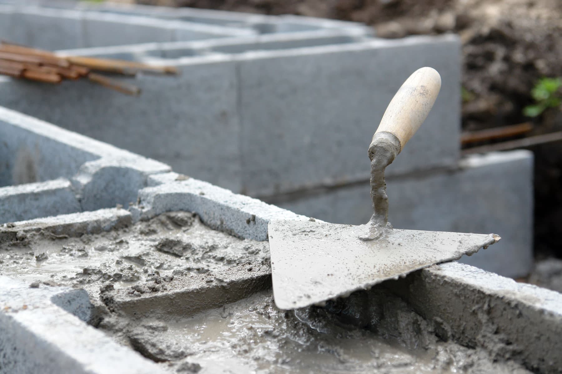 Masonry trowel resting on a freshly mortared concrete block wall