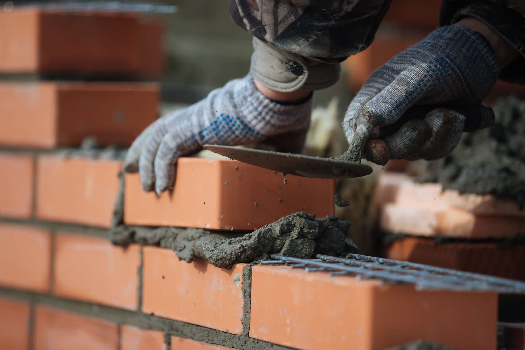 Mason pressing mortar into a brick joint with a trowel in Surrey, BC